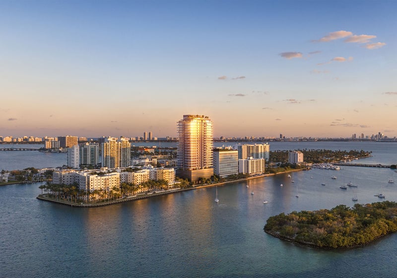 Sunset aerial of Pagani Residences in North Bay Village, Miami, Florida on Biscayne Bay, glowing tower against Miami skyline; luxury and ultra luxury preconstruction condos with waterfront views.