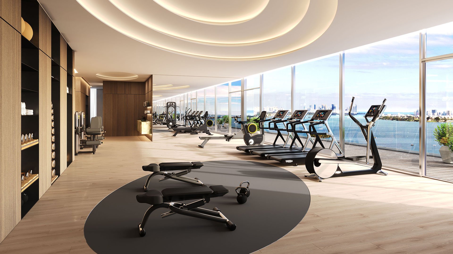 Pagani Residences fitness center gym in North Bay Village, Miami, Florida with treadmills, cardio and strength equipment and floor-to-ceiling bayfront windows; luxury and ultra luxury preconstruction condos amenities.