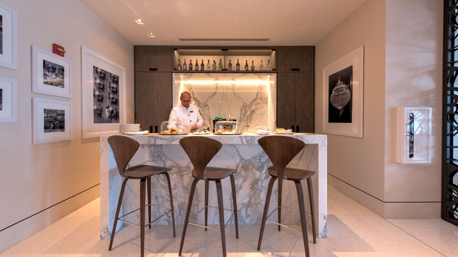 Attended lounge bar at Palazzo del Sol, Fisher Island, presenting luxury and ultra luxury condos with high stools, a stone counter, curated wall art, and a refined amenity space.