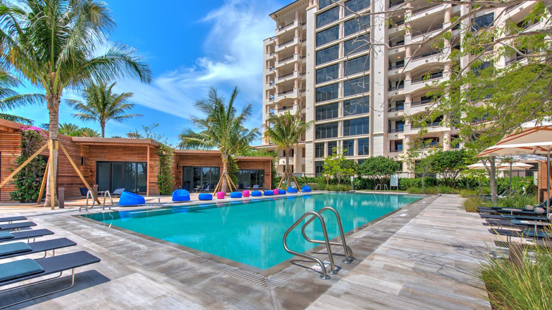 Pool terrace at Palazzo del Sol, Fisher Island, showing luxury and ultra luxury condos with a resort pool, shaded cabanas, palm landscaping, and the tower rising around the courtyard.