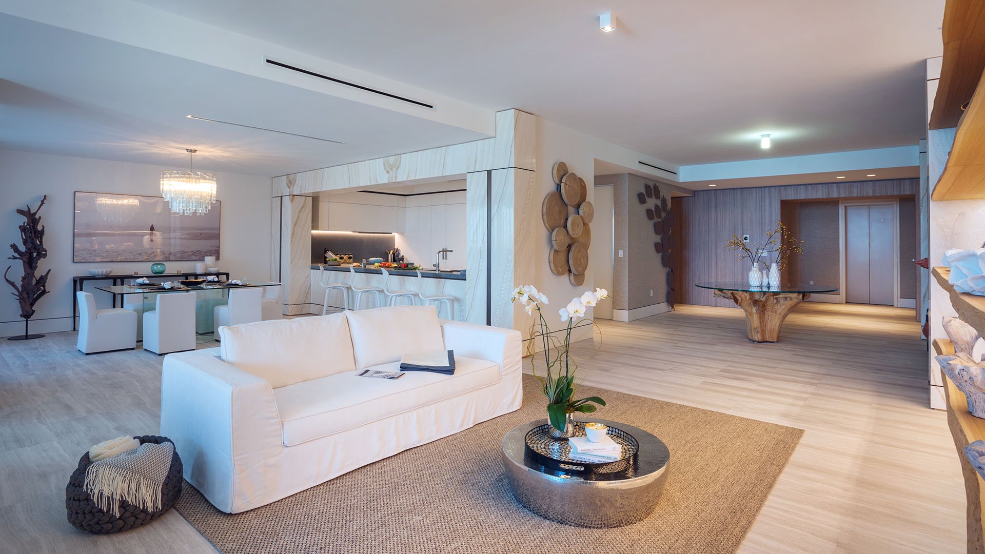 White sofa living room at Palazzo del Sol, Fisher Island, showcasing luxury and ultra luxury condos with a bright open kitchen, refined entry gallery, and warm modern finishes.