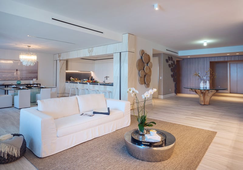 White sofa living room at Palazzo del Sol, Fisher Island, showcasing luxury and ultra luxury condos with a bright open kitchen, refined entry gallery, and warm modern finishes.