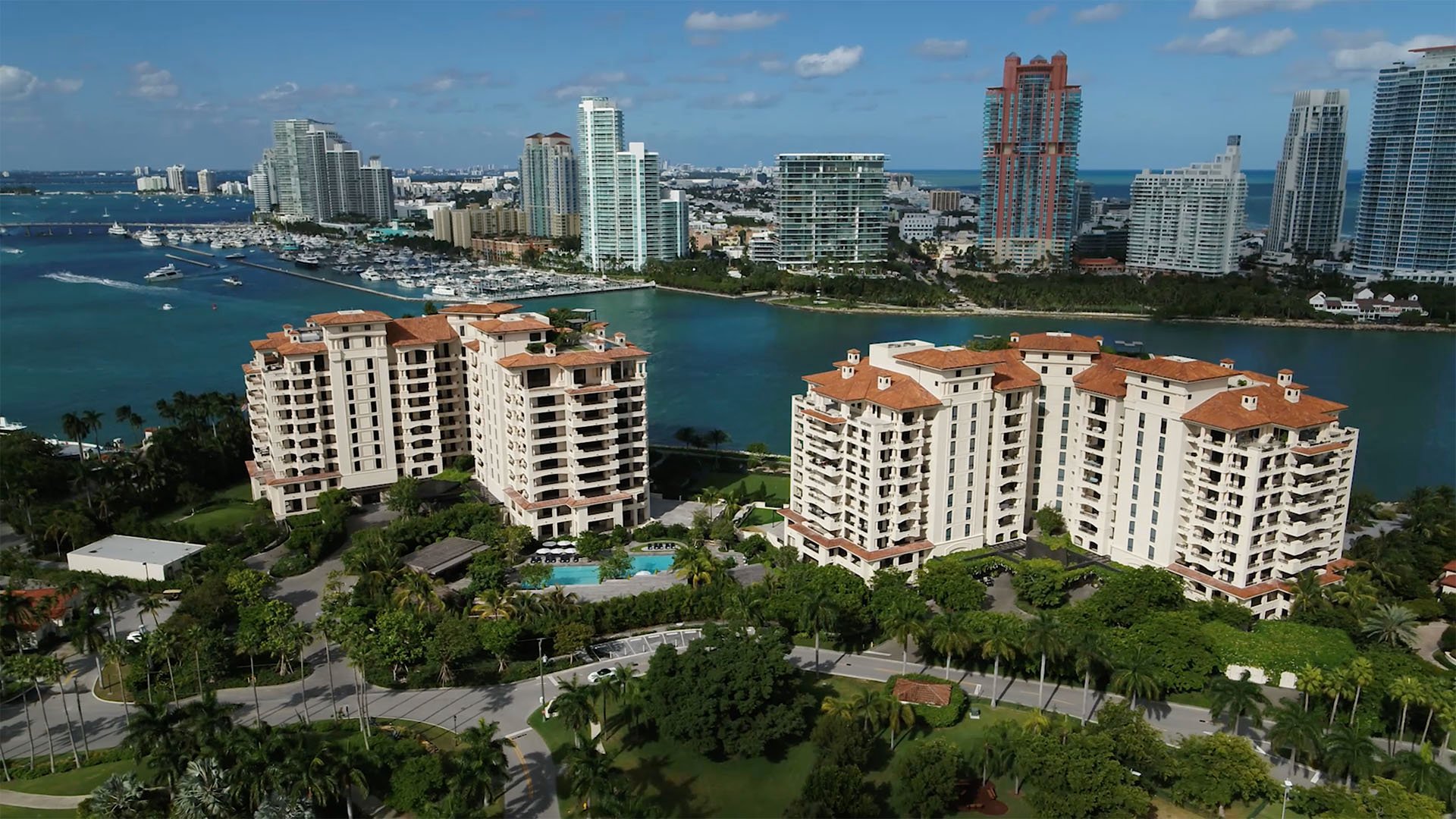 Palazzo della Luna in Fisher Island luxury and ultra luxury condos in an aerial view with bay water, neighboring towers, and the distant city skyline.