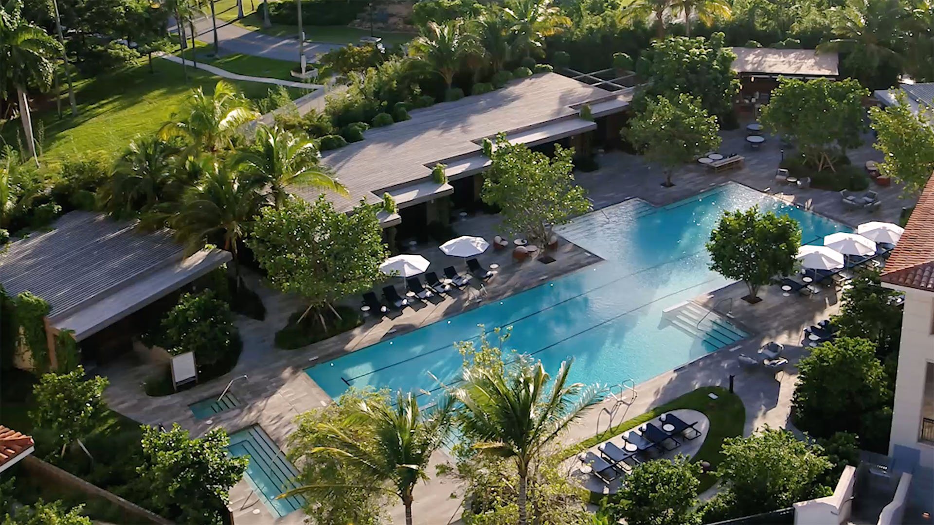 Palazzo della Luna in Fisher Island luxury and ultra luxury condos with an aerial pool terrace, cabanas, sun deck seating, and dense tropical landscaping.