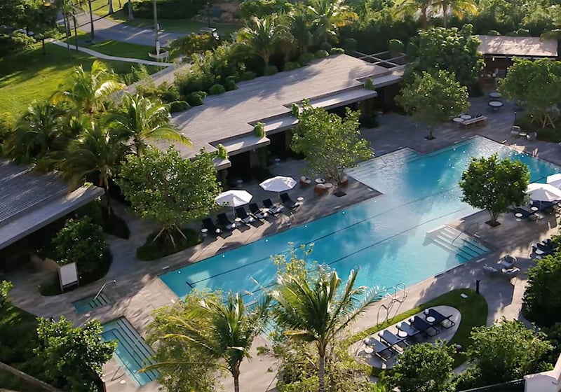 Palazzo della Luna in Fisher Island luxury and ultra luxury condos with an aerial pool terrace, cabanas, sun deck seating, and dense tropical landscaping.