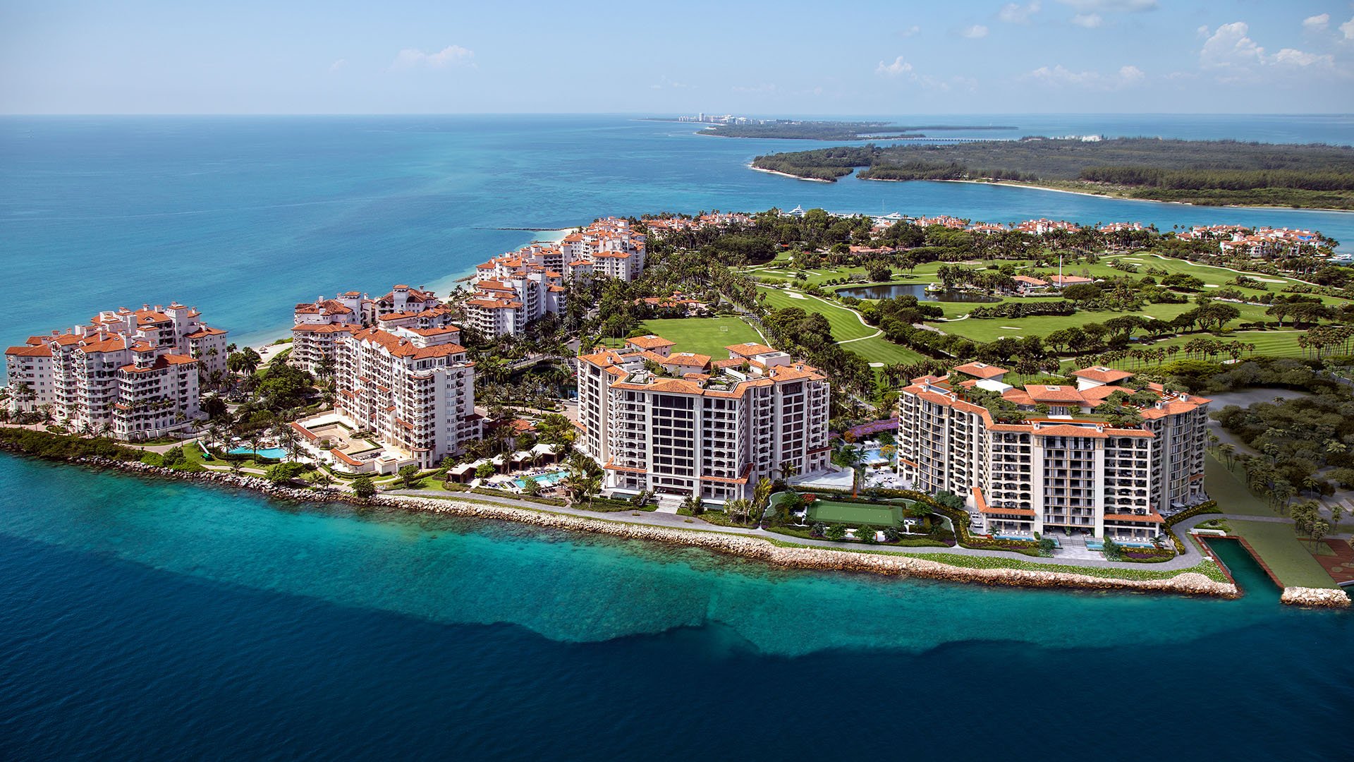 Palazzo della Luna in Fisher Island luxury and ultra luxury condos in an aerial waterfront view of the island residences surrounded by turquoise water and landscaped grounds.
