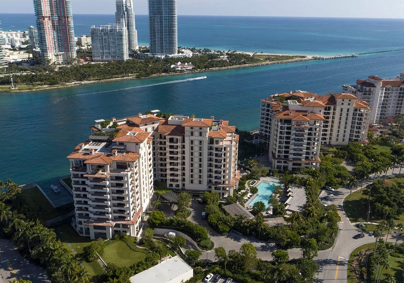Palazzo della Luna in Fisher Island luxury and ultra luxury condos in an aerial waterfront view with neighboring towers, marina water, and the city skyline.