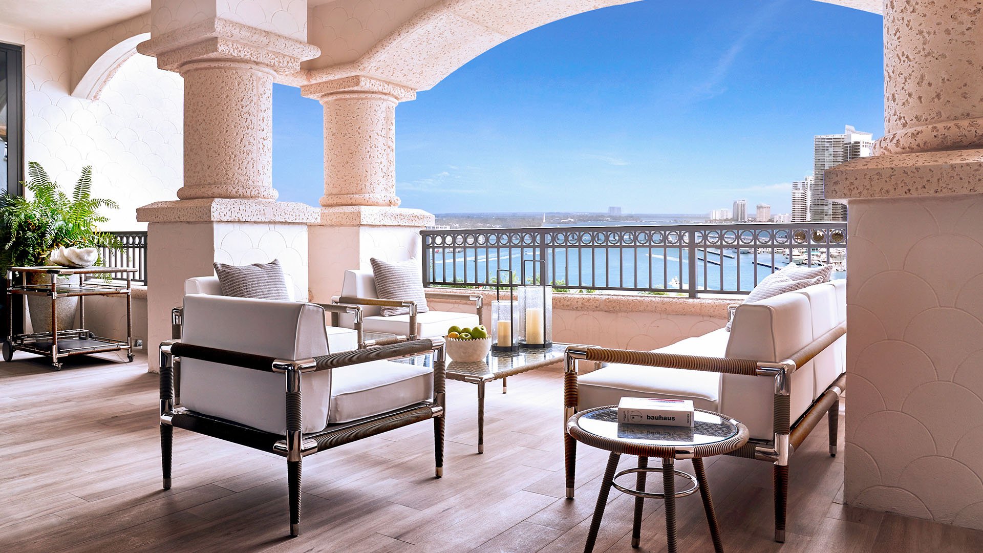 Palazzo della Luna in Fisher Island luxury and ultra luxury condos with an arched covered terrace, lounge seating, and a waterfront skyline view.