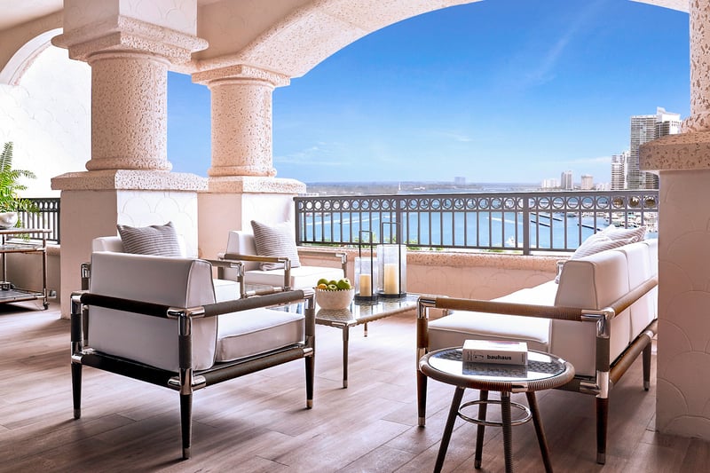 Palazzo della Luna in Fisher Island luxury and ultra luxury condos with an arched covered terrace, lounge seating, and a waterfront skyline view.