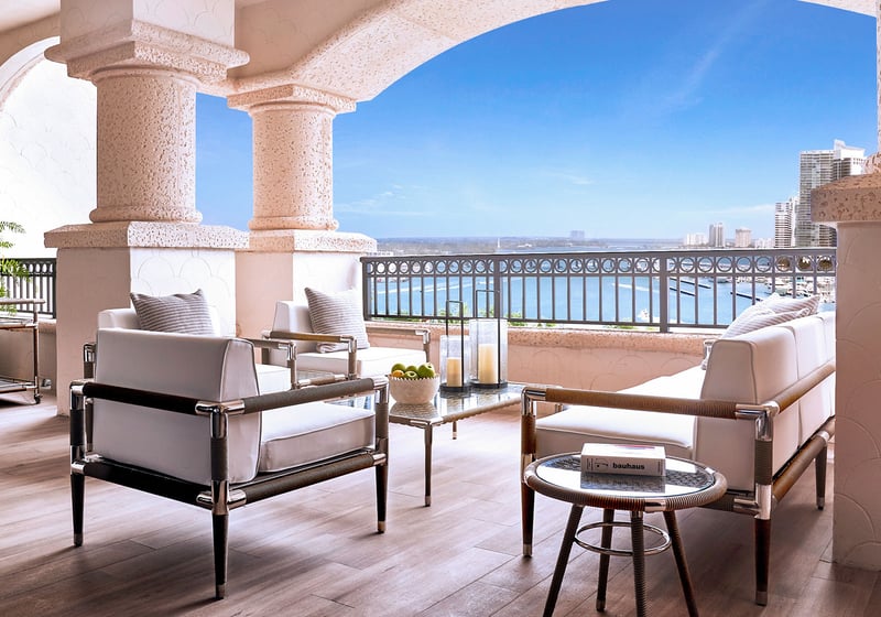 Palazzo della Luna in Fisher Island luxury and ultra luxury condos with an arched covered terrace, lounge seating, and a waterfront skyline view.