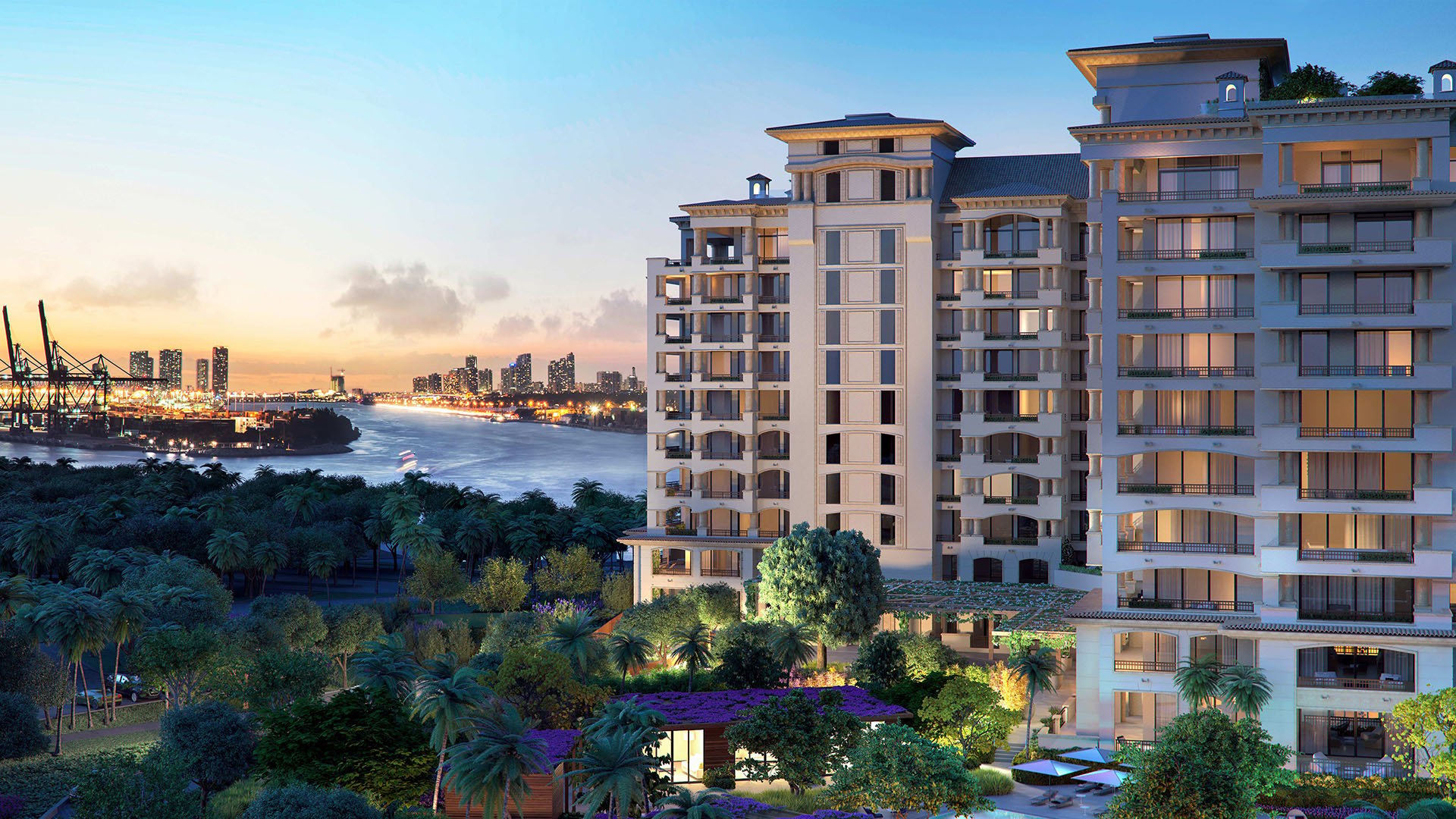 Palazzo della Luna in Fisher Island luxury and ultra luxury condos with a close waterfront exterior at sunset, glowing windows, tropical gardens, and a skyline backdrop.