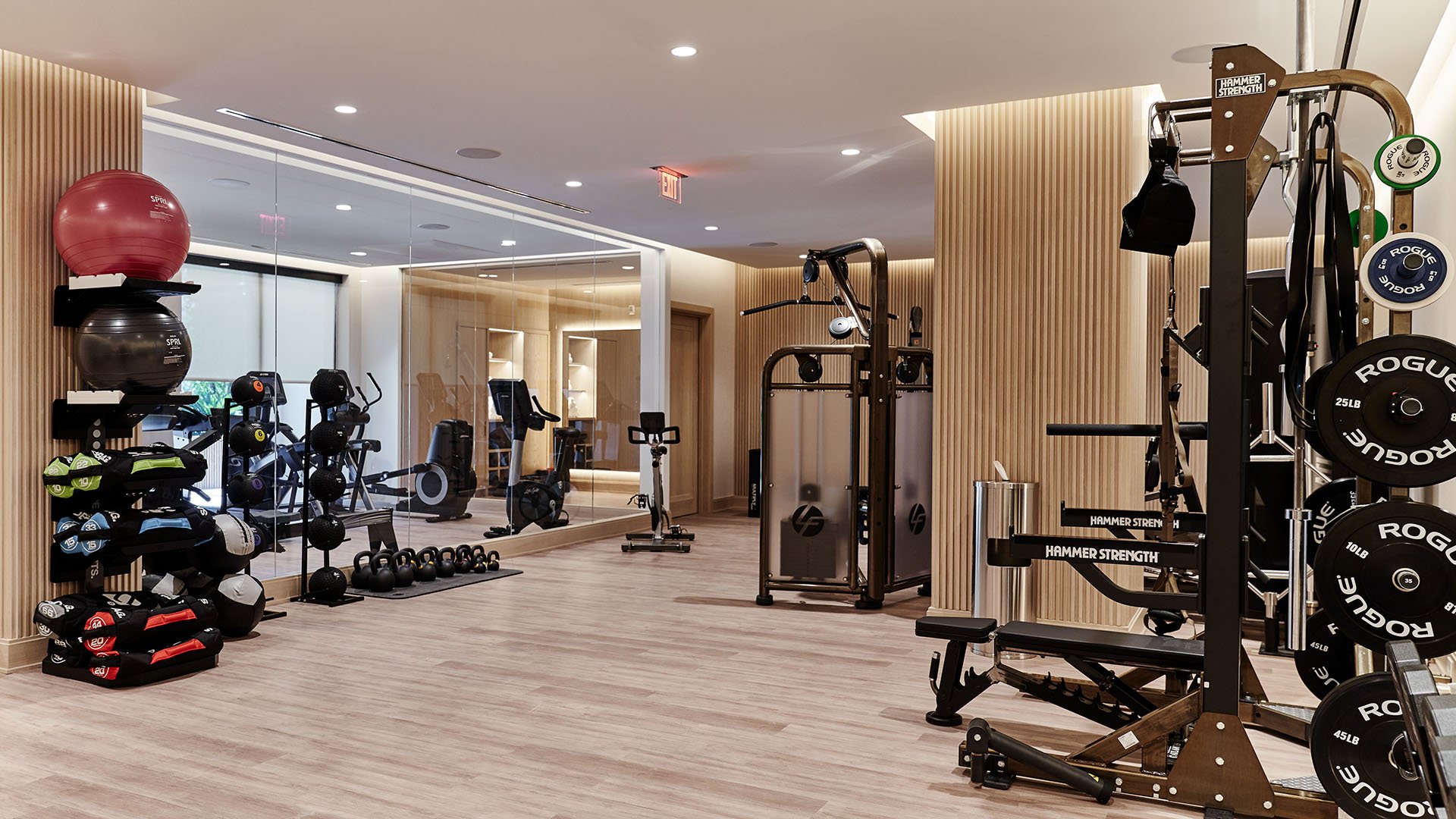 Palazzo della Luna in Fisher Island luxury and ultra luxury condos with a fitness center, strength training equipment, mirrors, and wood-toned finishes.