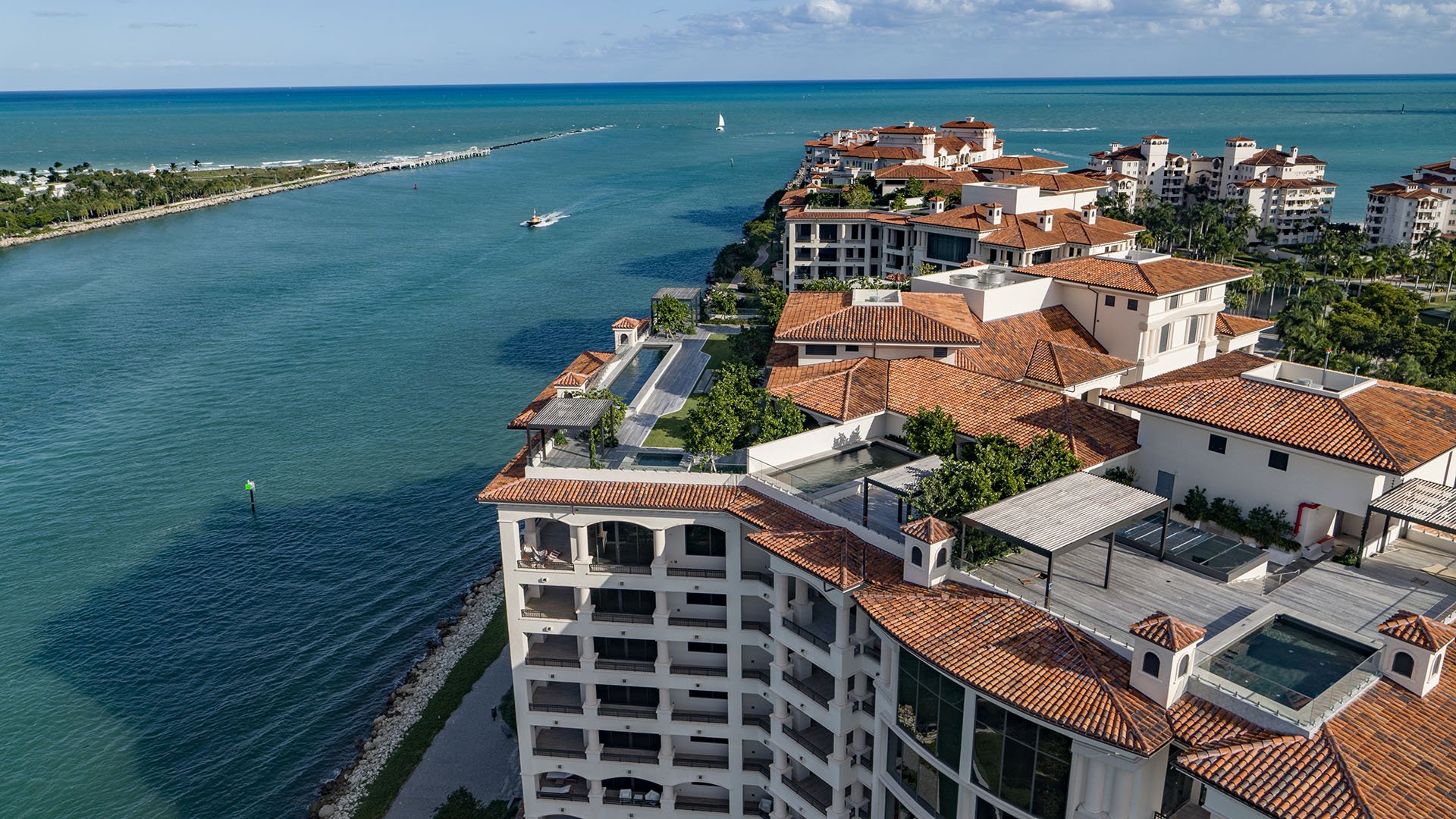 Palazzo della Luna in Fisher Island luxury and ultra luxury condos in a rooftop aerial view facing the waterfront channel, penthouse terraces, and open water.