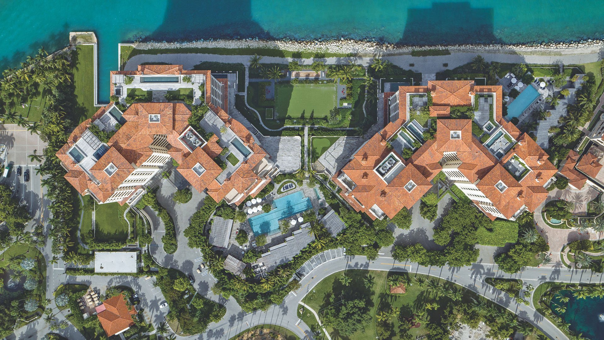 Palazzo della Luna in Fisher Island luxury and ultra luxury condos in a top-down aerial of the full waterfront complex, seawall, pool, and landscaped arrival drives.