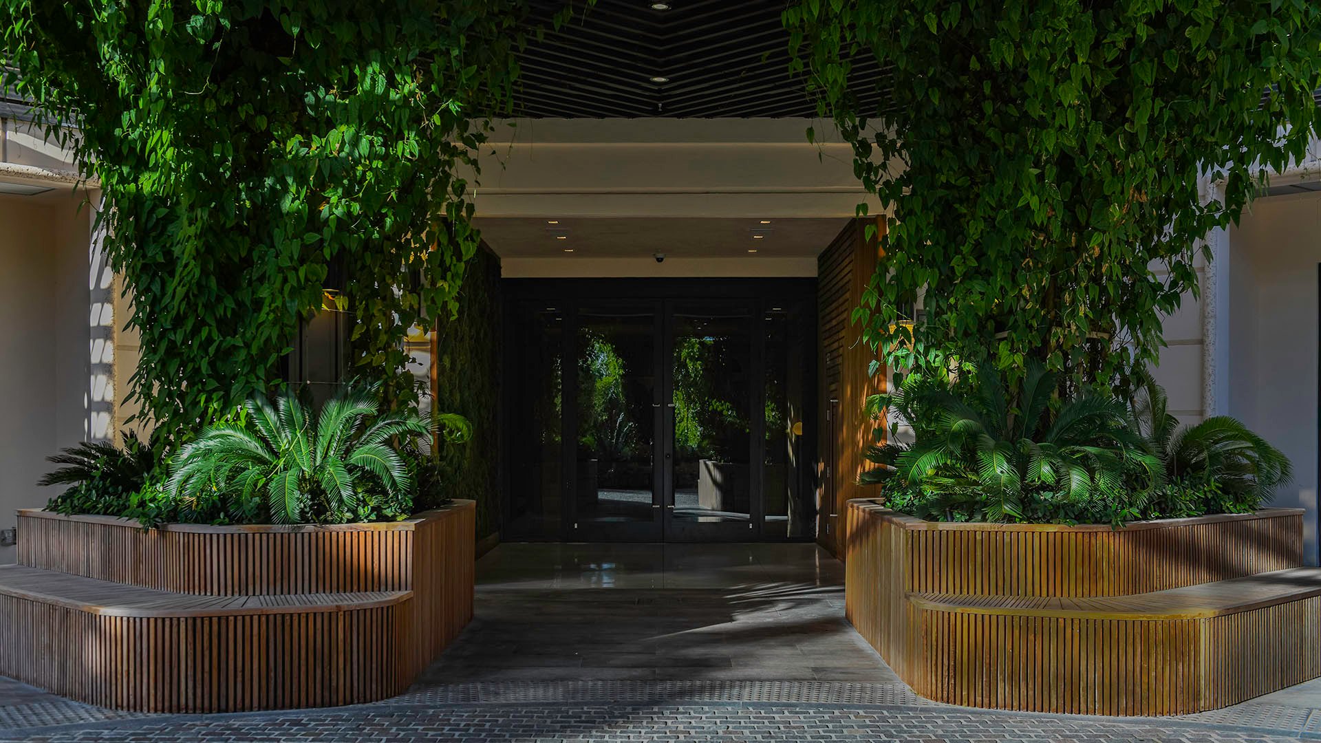 Palazzo della Luna in Fisher Island luxury and ultra luxury condos with a vine-covered entry portico, oversized planters, and a shaded arrival court.