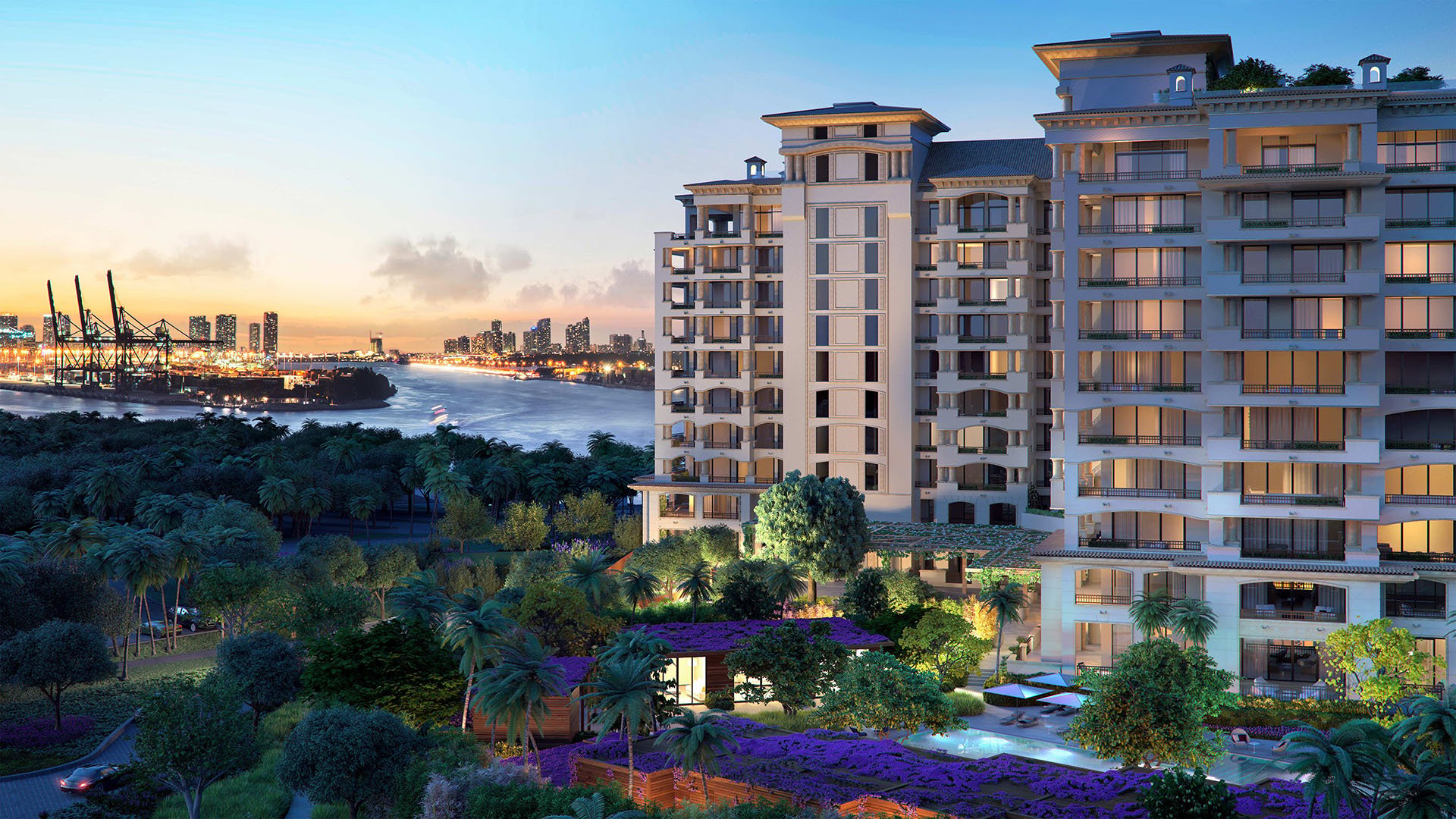 Palazzo della Luna in Fisher Island luxury and ultra luxury condos with a wide waterfront exterior at sunset, glowing tower windows, tropical grounds, and a skyline backdrop.
