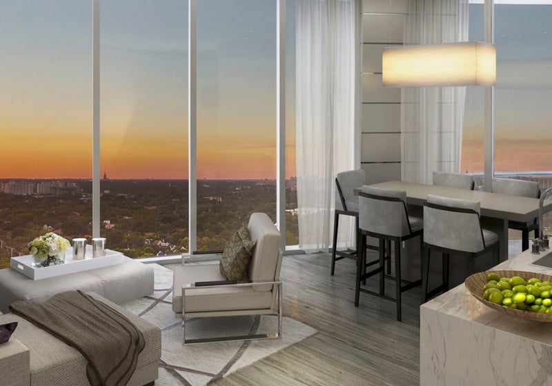 Compact living room with a kitchen island, dining nook and sunset skyline view at Park Grove in Coconut Grove, illustrating efficient luxury and ultra luxury condos interiors.