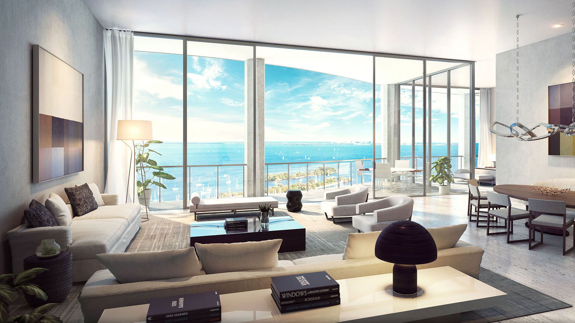 Glass-wall living room with terrace dining, modern art and expansive blue water views at Park Grove in Coconut Grove, representing luxury and ultra luxury condos.