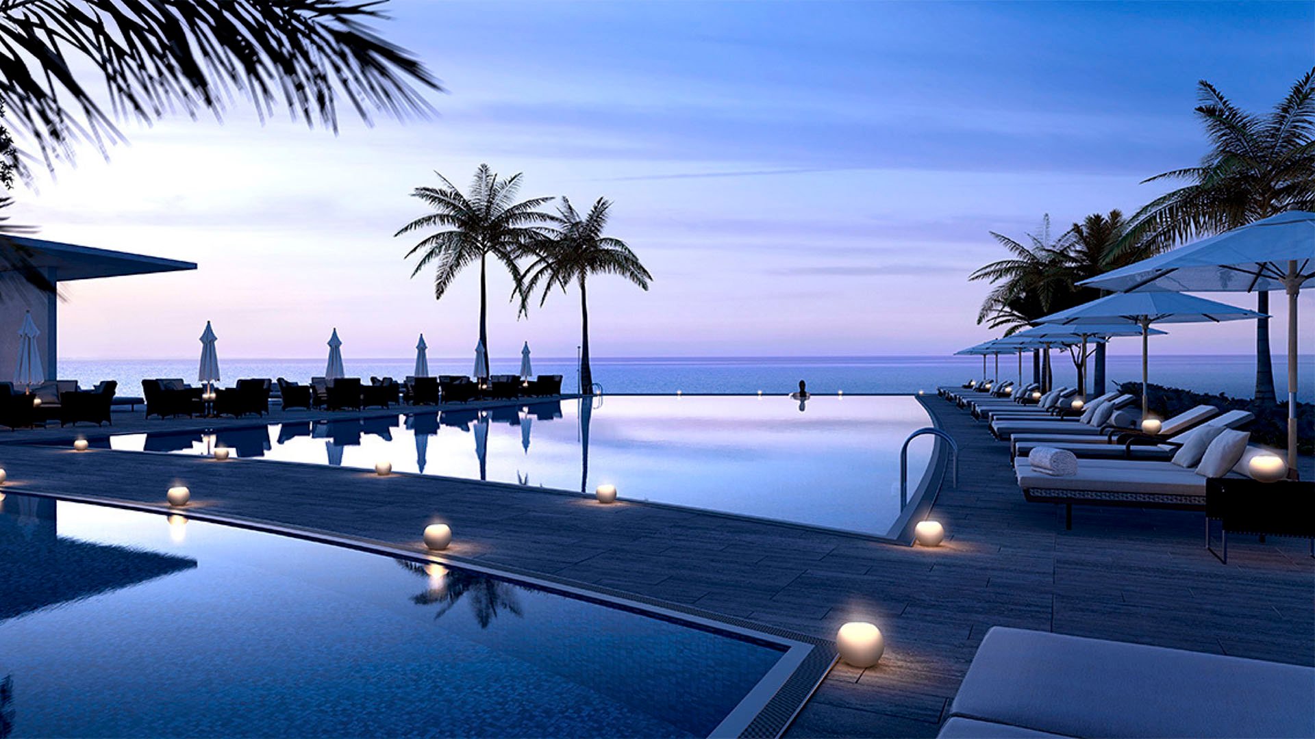 Infinity pool deck at dusk with palms, loungers and glowing lights over the water at Park Grove in Coconut Grove, complementing the luxury and ultra luxury condos lifestyle.