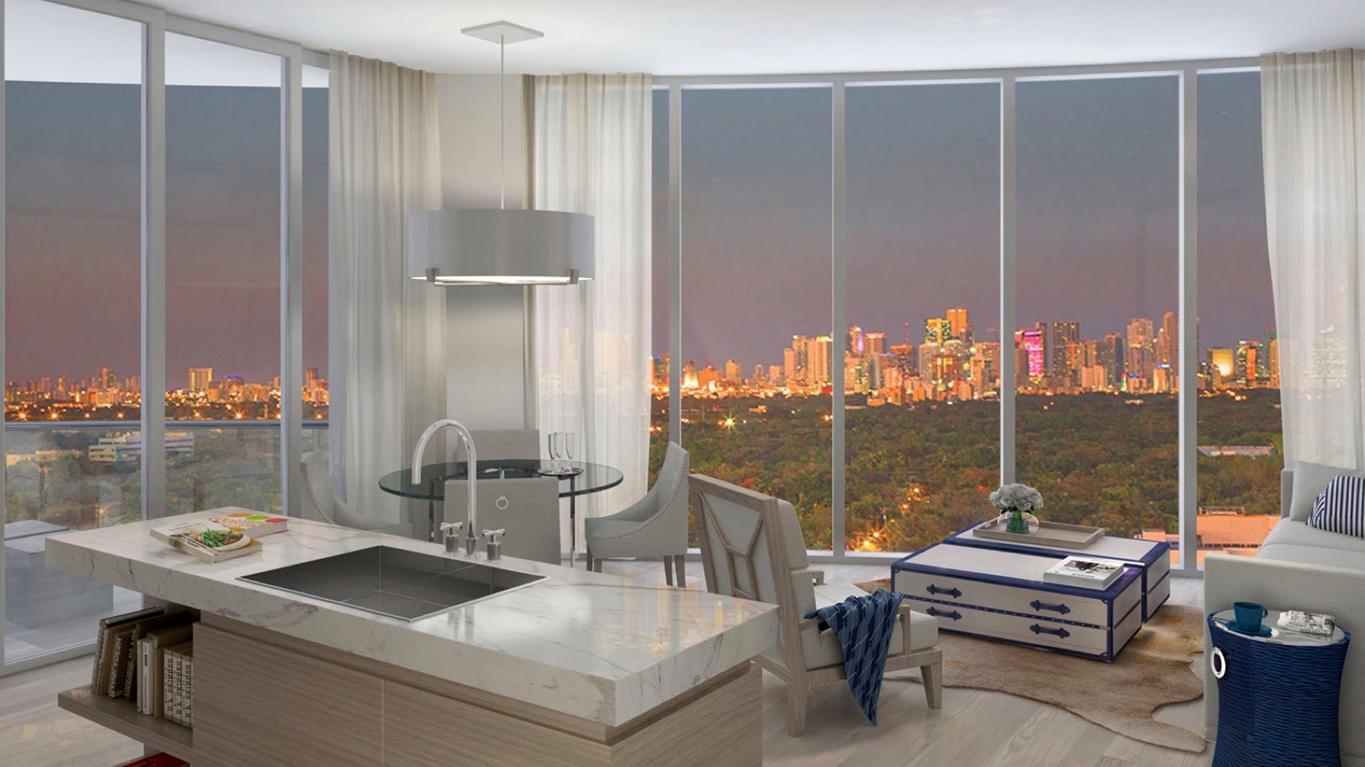 Kitchen island great room with a city skyline at dusk, floor-to-ceiling glass and lounge seating at Park Grove in Coconut Grove, defining luxury and ultra luxury condos living.