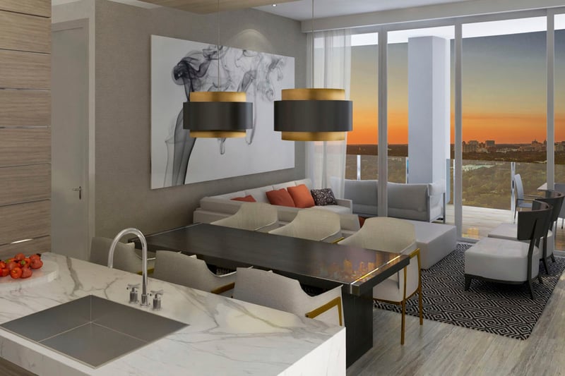 Sunset kitchen, dining and living room with a terrace, marble island and warm skyline glow at Park Grove in Coconut Grove, presenting luxury and ultra luxury condos interiors.