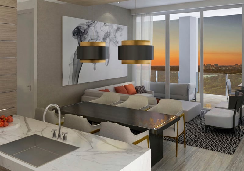 Sunset kitchen, dining and living room with a terrace, marble island and warm skyline glow at Park Grove in Coconut Grove, presenting luxury and ultra luxury condos interiors.