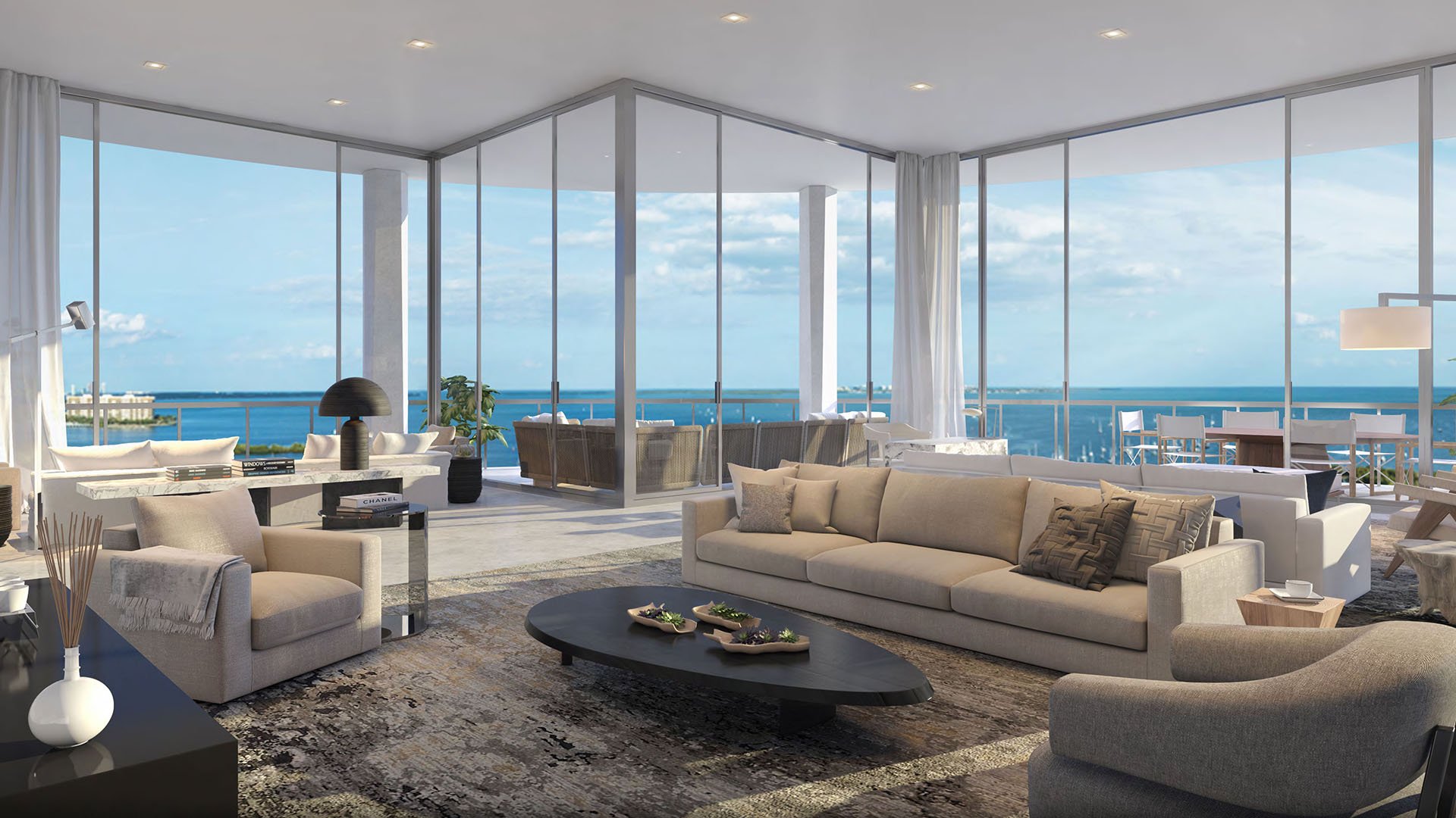 Wraparound glass living room with layered seating, a broad terrace and open bayfront views at Park Grove in Coconut Grove, expressing the luxury and ultra luxury condos design.