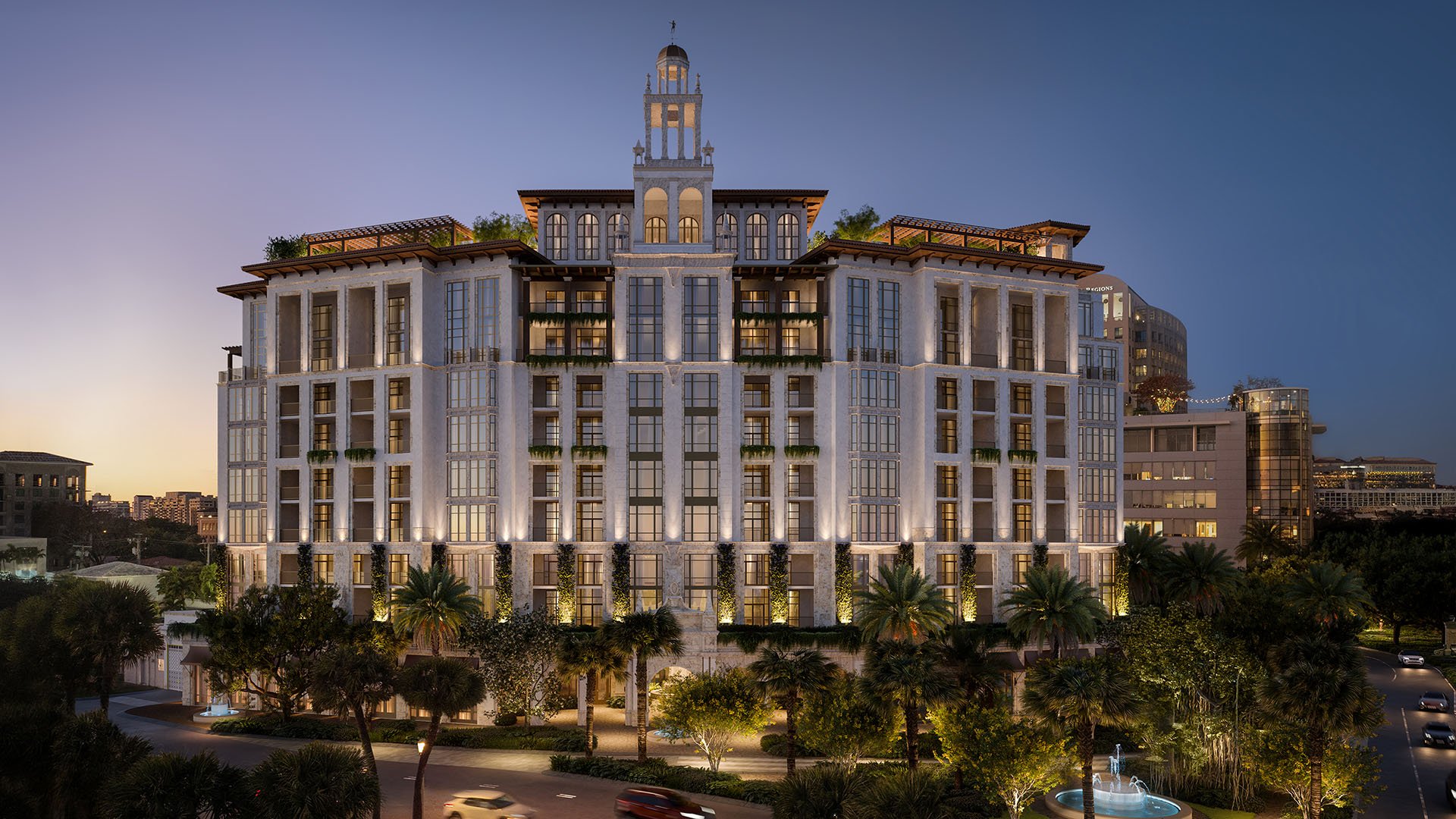 Ponce Park Residences Coral Gables, Miami main facade at twilight with landscaped entrance, palm trees and fountain, spotlighting luxury and ultra luxury preconstruction condos in downtown Coral Gables.