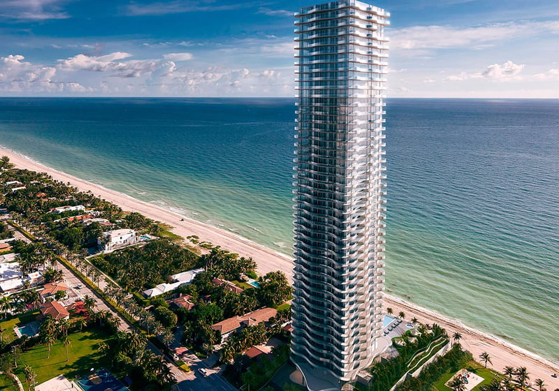Aerial waterfront view of Regalia in Sunny Isles Beach, where luxury and ultra luxury condos rise beside a long sandy coastline and turquoise ocean water.