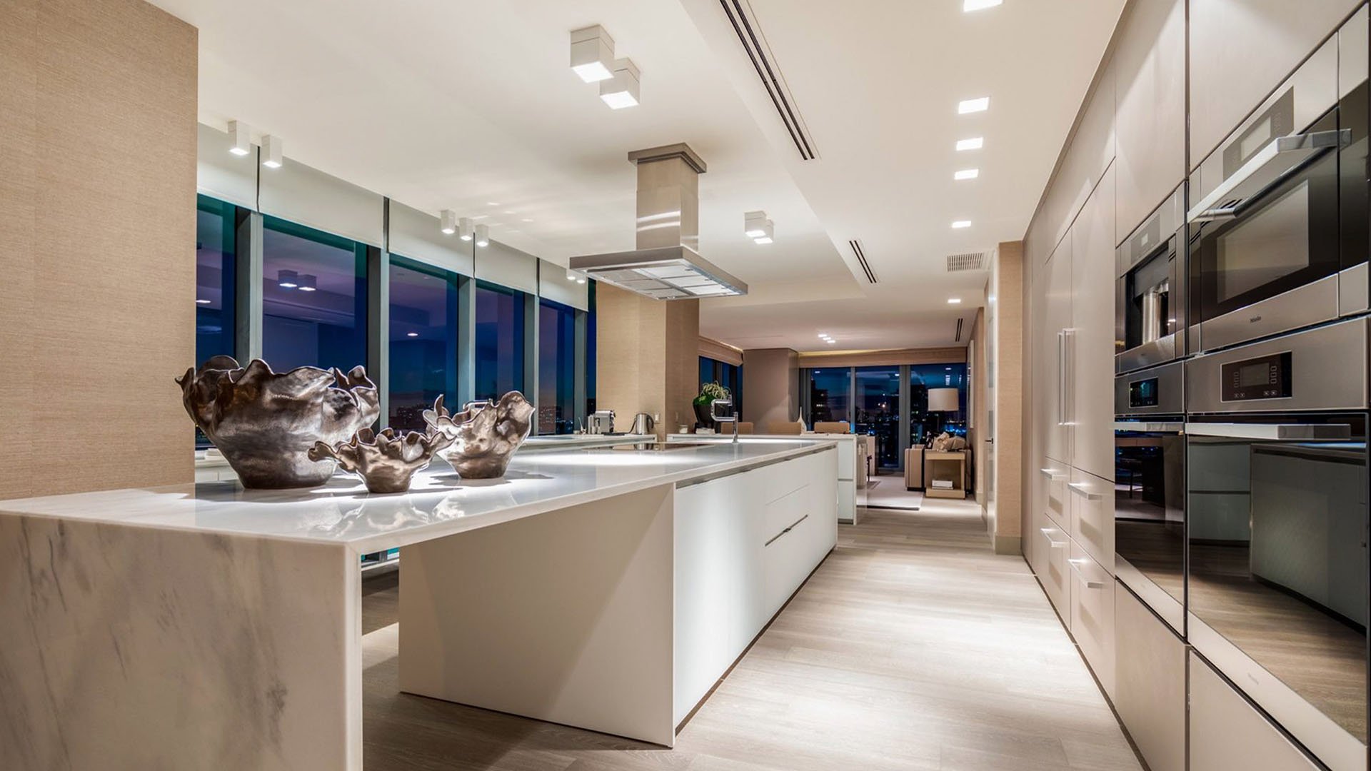 Warm contemporary chef kitchen at Regalia in Sunny Isles Beach with a central island, built-in appliances, and ambient lighting in luxury and ultra luxury condos.