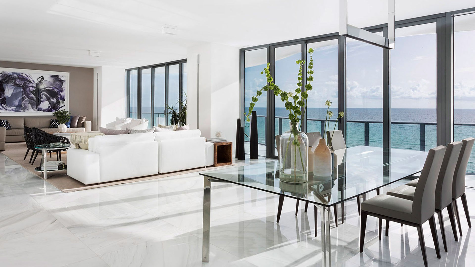 Corner living and dining space at Regalia in Sunny Isles Beach with marble floors, white seating, and oceanfront glass walls in luxury and ultra luxury condos.