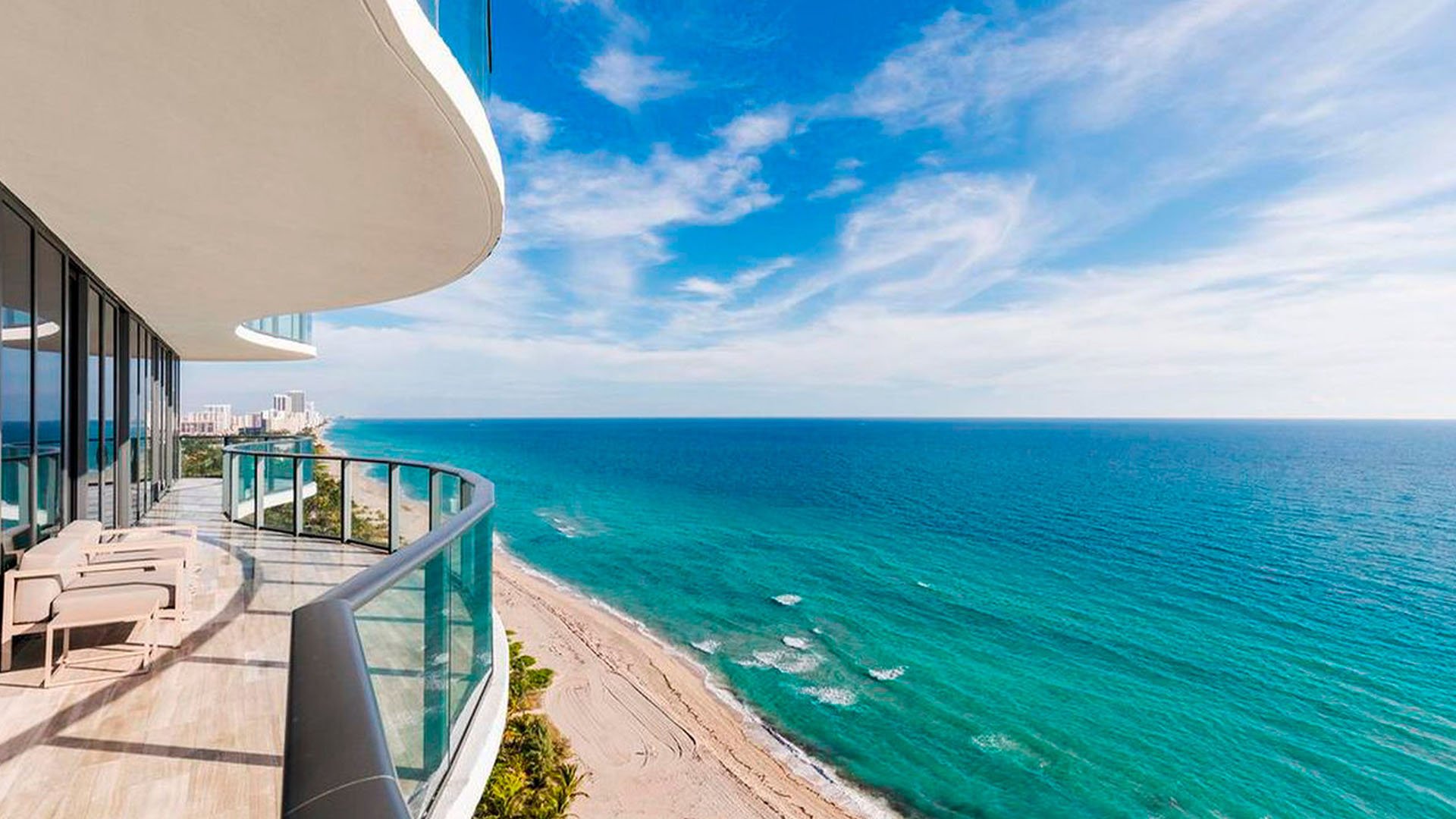 Expansive curved terrace at Regalia in Sunny Isles Beach with chaise loungers and panoramic oceanfront views from luxury and ultra luxury condos.