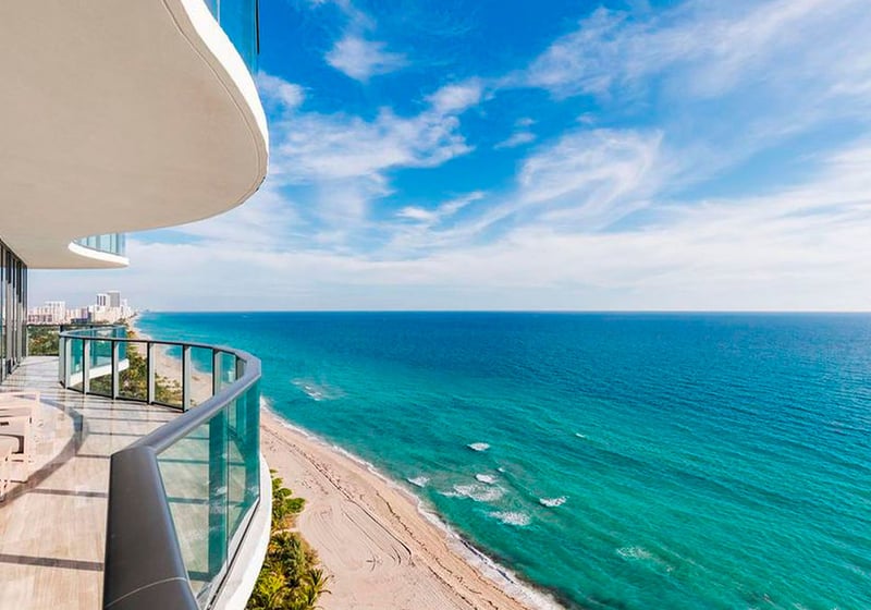 Expansive curved terrace at Regalia in Sunny Isles Beach with chaise loungers and panoramic oceanfront views from luxury and ultra luxury condos.