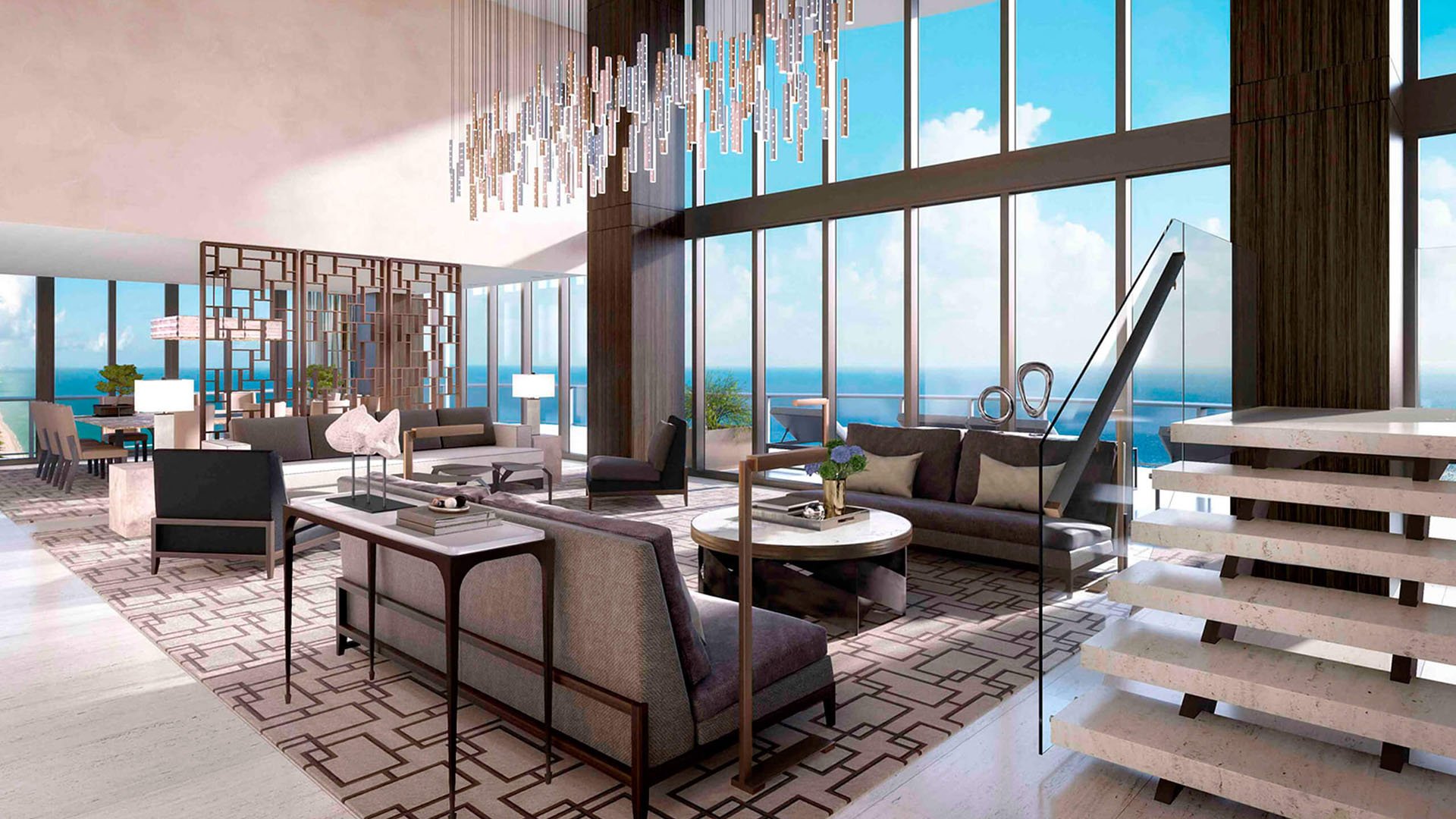 Double-height living room at Regalia in Sunny Isles Beach with a floating staircase, large chandelier, and ocean views inside luxury and ultra luxury condos.
