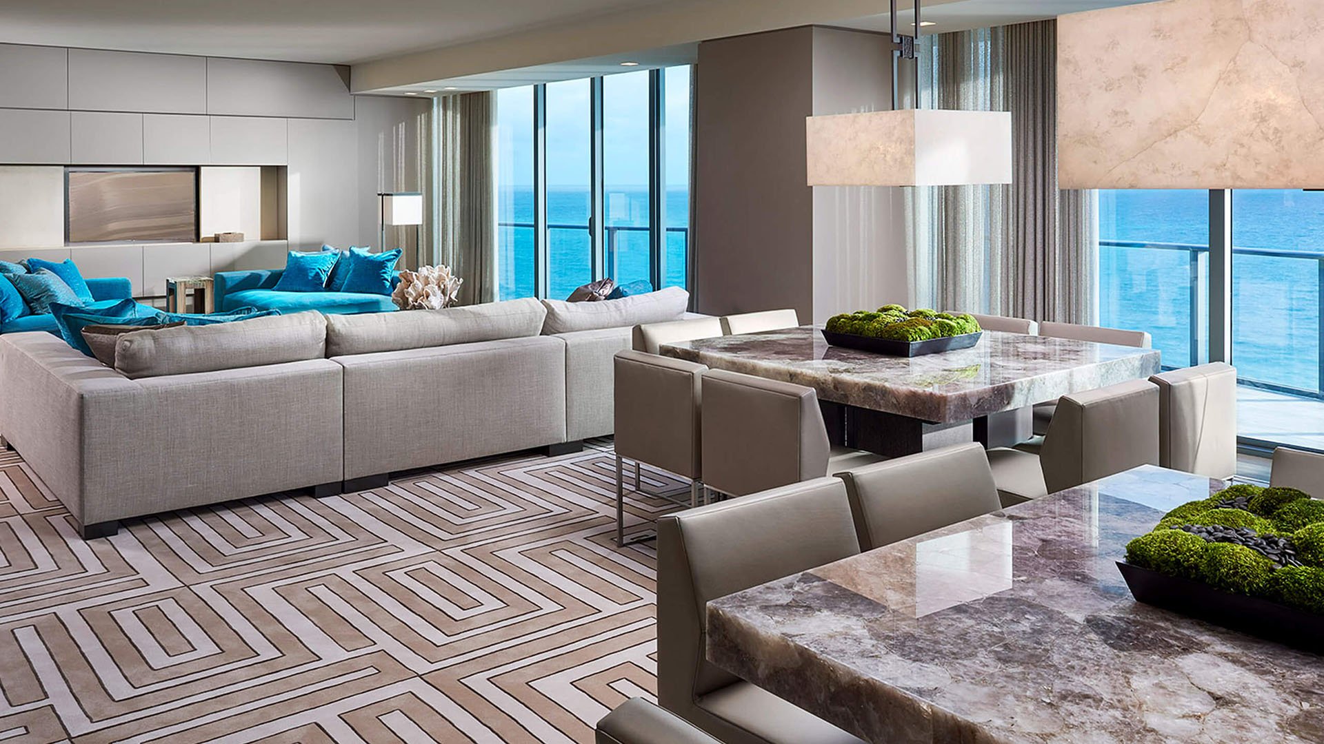 Great room and dining area at Regalia in Sunny Isles Beach with ocean views, a patterned rug, and expansive seating in luxury and ultra luxury condos.