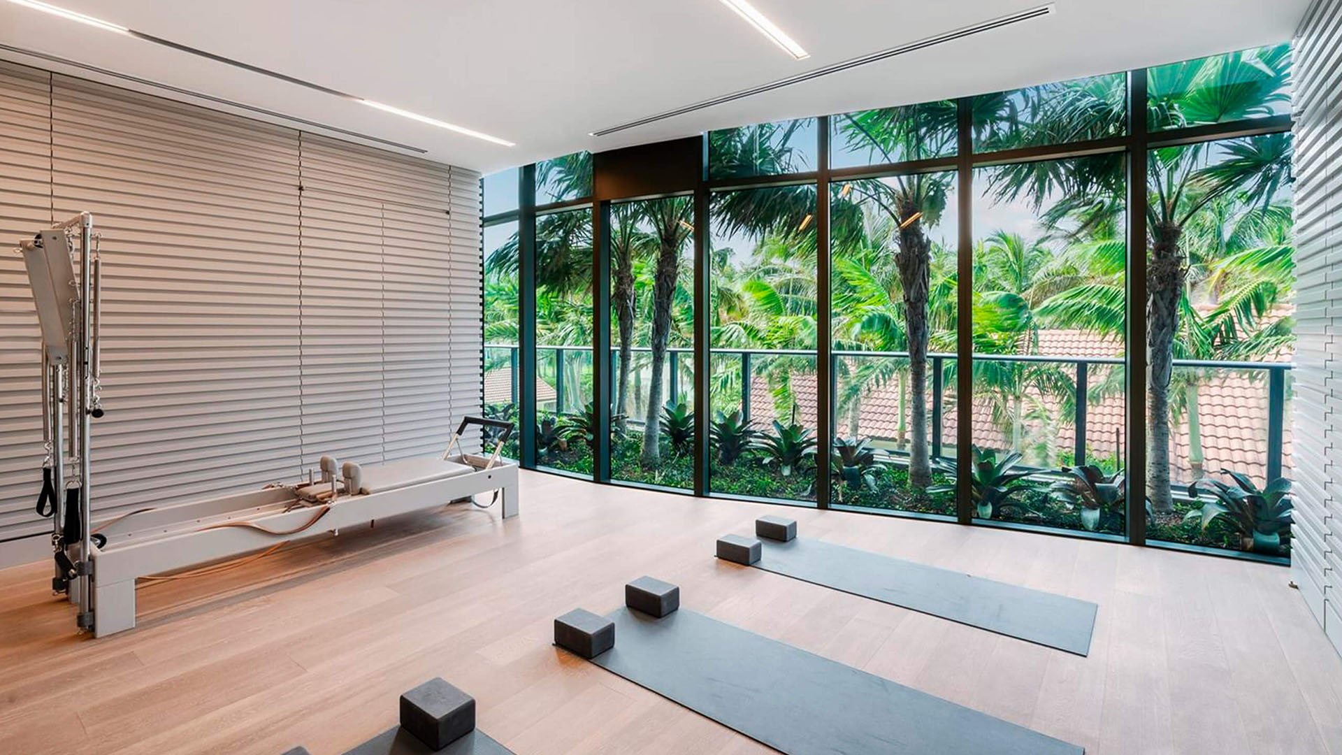 Pilates and yoga studio at Regalia in Sunny Isles Beach with reformer equipment, mats, and lush palm views for luxury and ultra luxury condos.