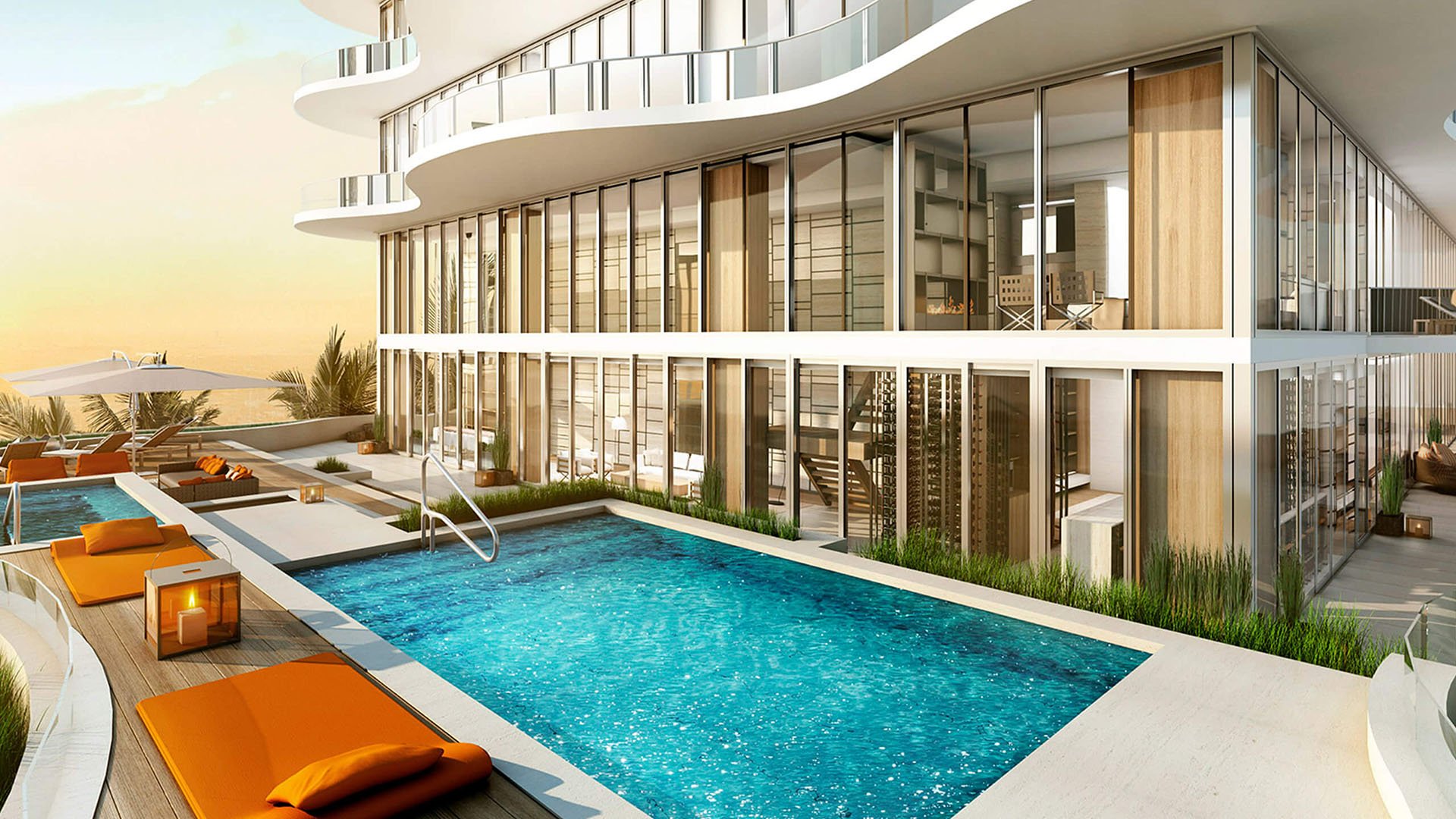 Pool terrace at Regalia in Sunny Isles Beach with orange loungers, a sleek rectangular pool, and glass-wrapped architecture for luxury and ultra luxury condos.