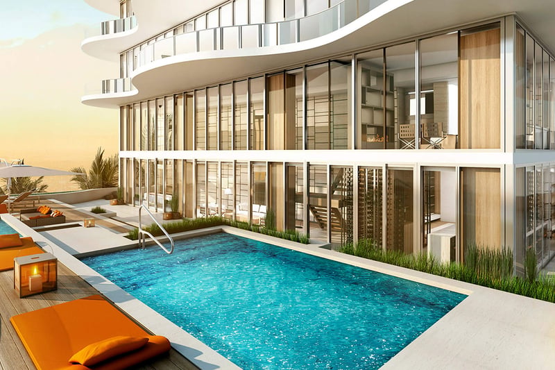 Pool terrace at Regalia in Sunny Isles Beach with orange loungers, a sleek rectangular pool, and glass-wrapped architecture for luxury and ultra luxury condos.