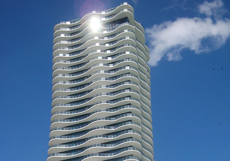Sunlit tower closeup at Regalia in Sunny Isles Beach showing the sculpted curved balconies and glass facade of luxury and ultra luxury condos.