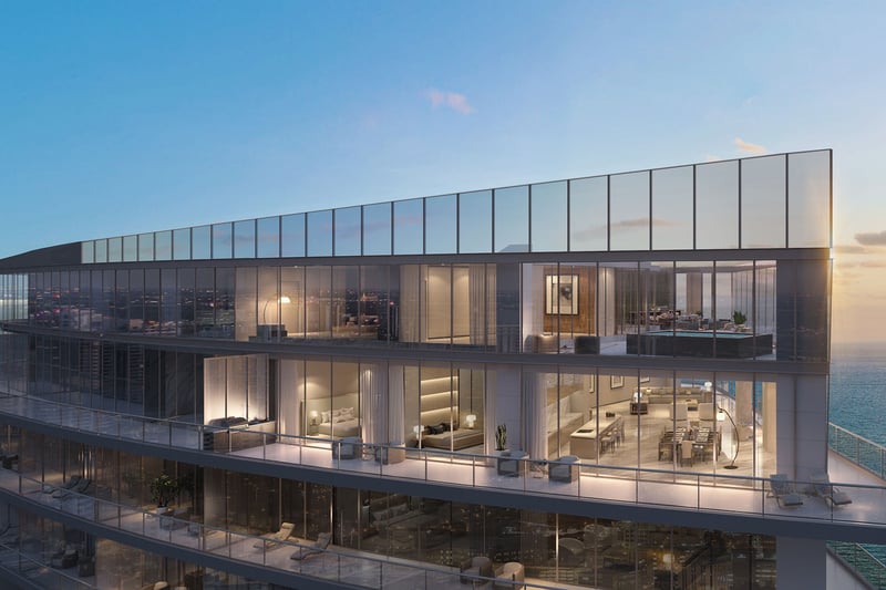 Residences by Armani Casa, Sunny Isles Beach luxury and ultra luxury preconstruction condos, glass-wrapped multi-level exterior with illuminated interiors, expansive terraces, and open ocean views at sunset.