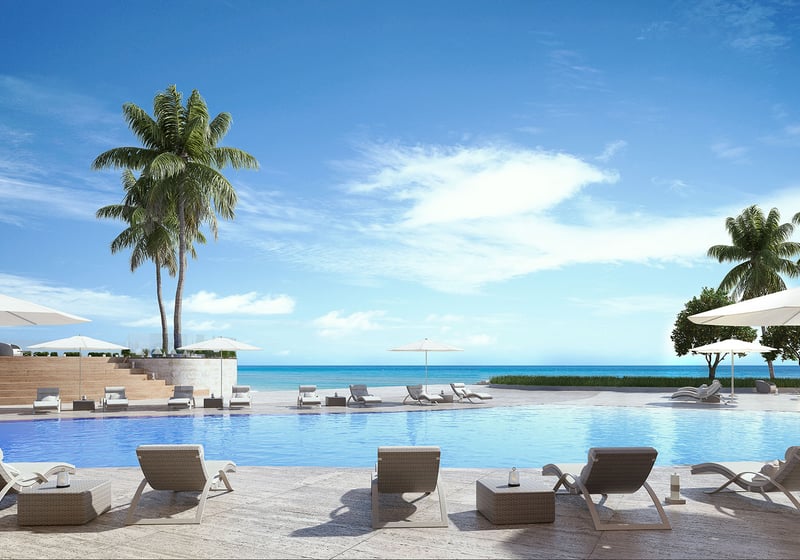 Residences by Armani Casa, Sunny Isles Beach luxury and ultra luxury preconstruction condos, resort-style pool terrace with loungers, umbrellas, palms, and a direct beachfront view.