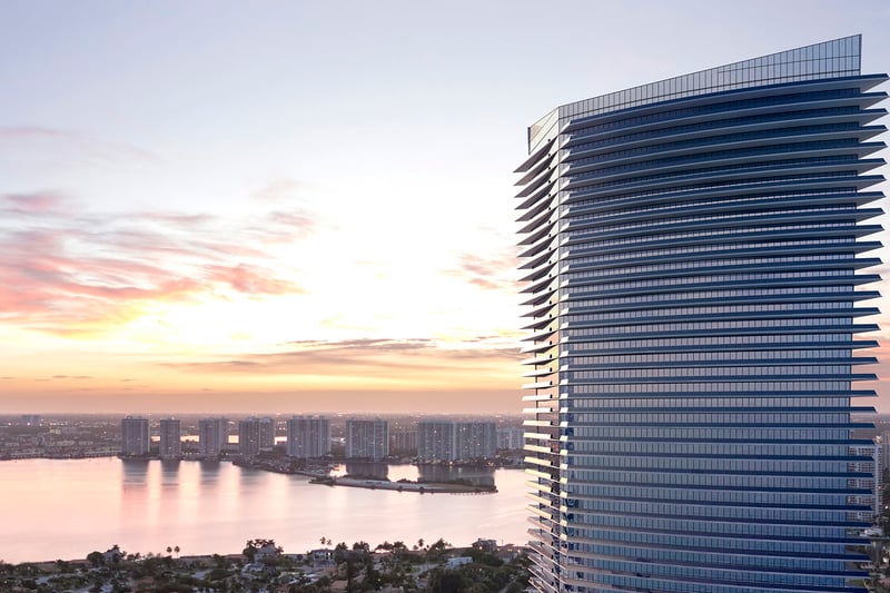 Residences by Armani Casa, Sunny Isles Beach luxury and ultra luxury preconstruction condos, sunset exterior of the sculpted tower with waterfront skyline views and glowing bands of glass balconies.