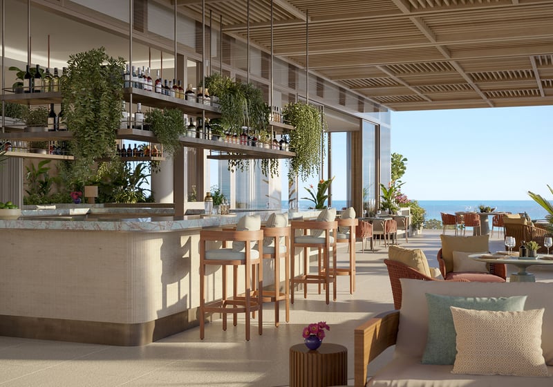 Open-air oceanfront bar terrace at Rosewood Residences Hillsboro Beach, Florida with bar stools, hanging bottle shelves and greenery under a slatted ceiling, Atlantic view, luxury and ultra luxury preconstruction condos.