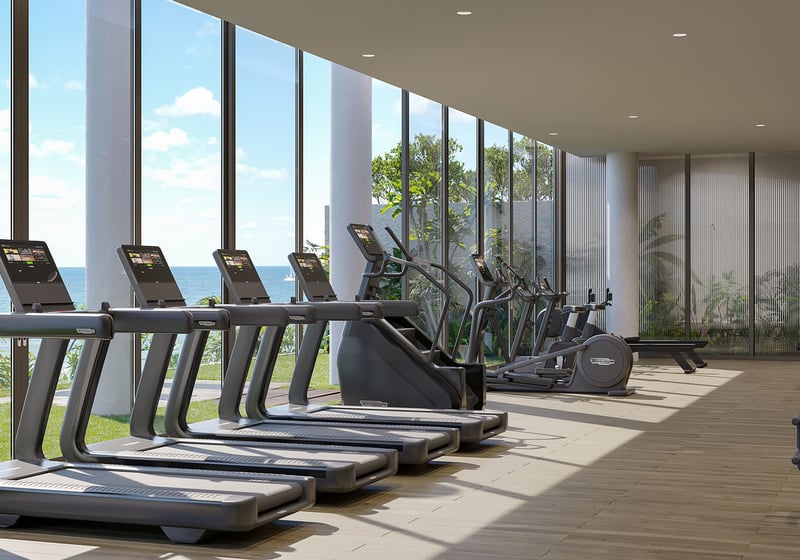 Oceanfront fitness center at Rosewood Residences Hillsboro Beach, Florida with treadmills and cardio equipment by floor-to-ceiling windows overlooking the Atlantic, luxury and ultra luxury preconstruction condos.