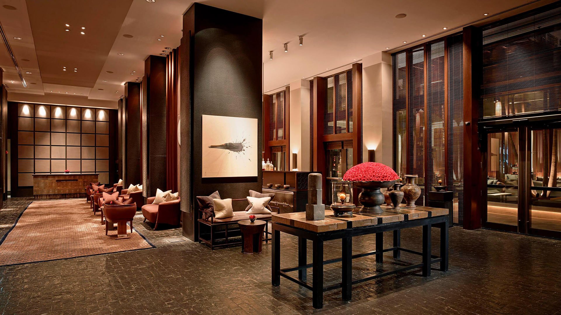 Lobby lounge at Setai Miami Beach in Miami Beach reflecting luxury and ultra luxury condos with soaring ceilings, dark wood paneling, designer seating, and sculptural decor.