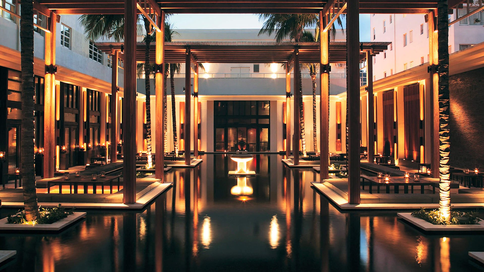 Illuminated entry courtyard at Setai Miami Beach in Miami Beach showcasing luxury and ultra luxury condos with reflecting water, glowing columns, palm trees, and a serene open-air arrival sequence.
