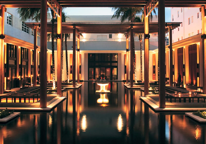 Illuminated entry courtyard at Setai Miami Beach in Miami Beach showcasing luxury and ultra luxury condos with reflecting water, glowing columns, palm trees, and a serene open-air arrival sequence.