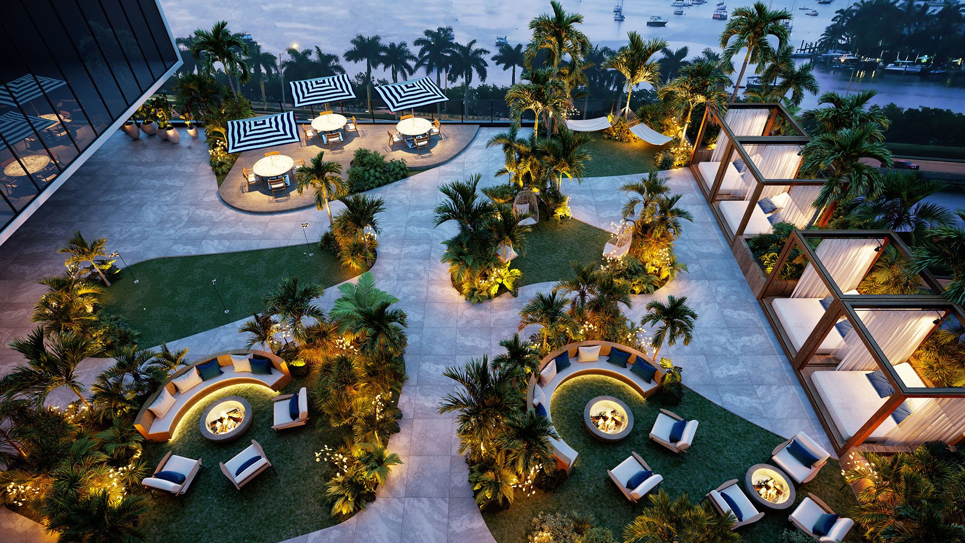 Aerial view of Shoma Bay North Bay Village rooftop zen garden amenity deck at dusk with fire pit lounges, cabanas, striped umbrellas and tropical landscaping overlooking Biscayne Bay, highlighting luxury and ultra luxury preconstruction condos in Miami.