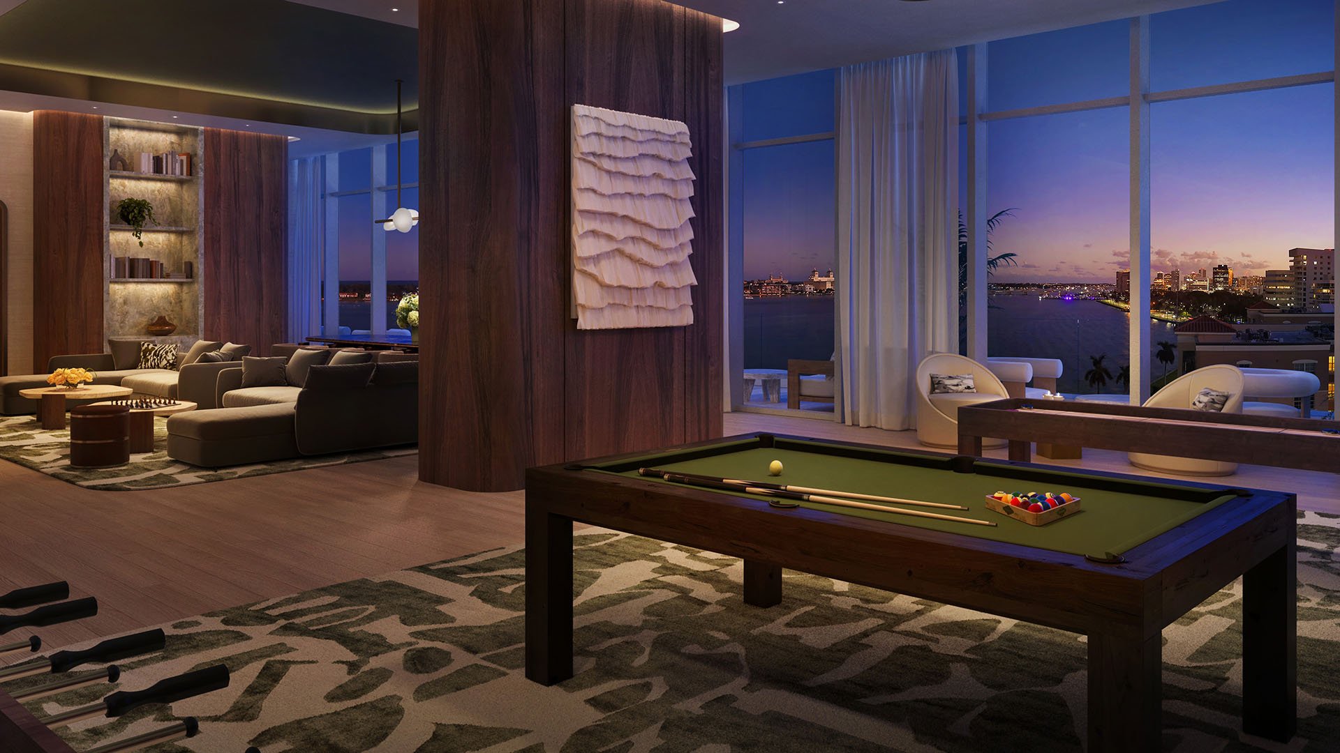 Shorecrest Flagler Drive game lounge in West Palm Beach, Florida, with billiards pool table, plush seating and waterfront night skyline views - luxury and ultra luxury preconstruction condos social amenity.