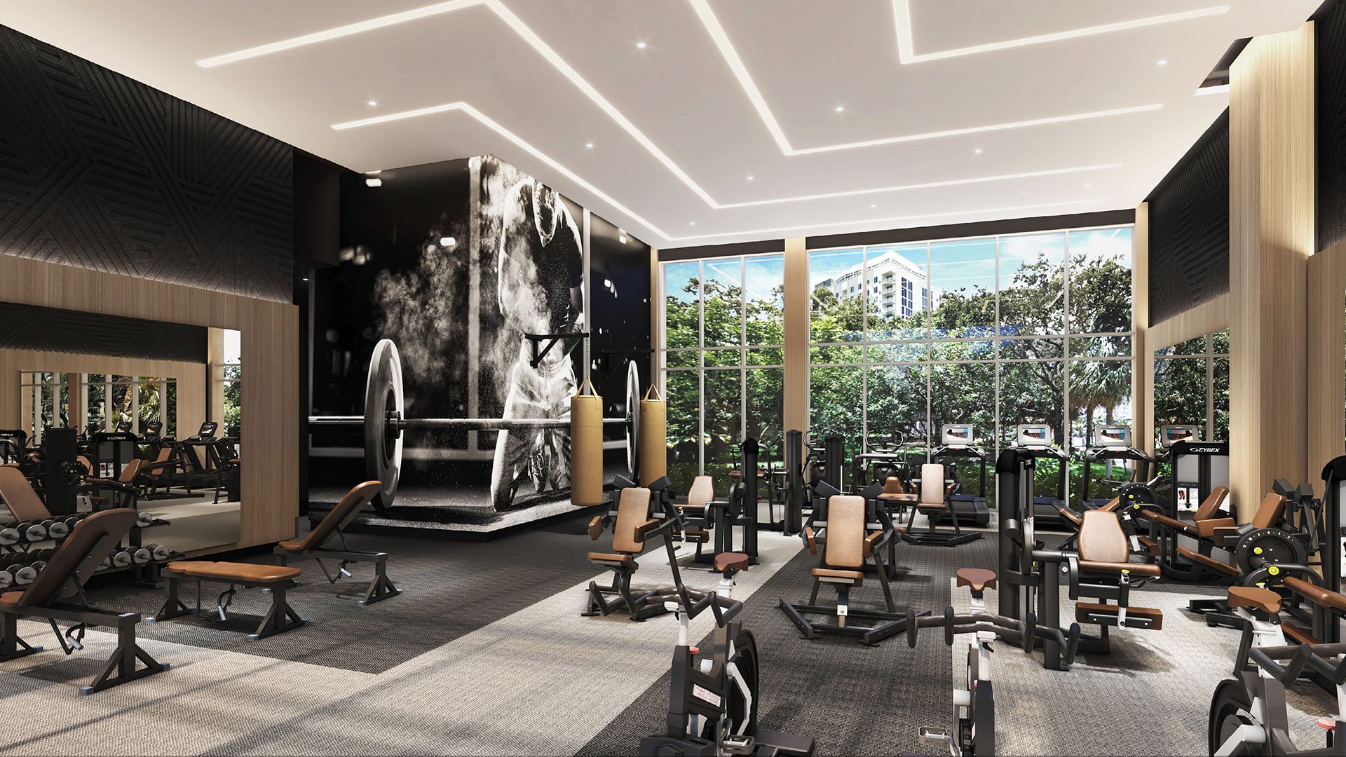 Sixth & Rio luxury and ultra luxury preconstruction condos in Fort Lauderdale, Florida, fitness center with strength machines, free weights and cardio equipment under dramatic lighting and tall windows.